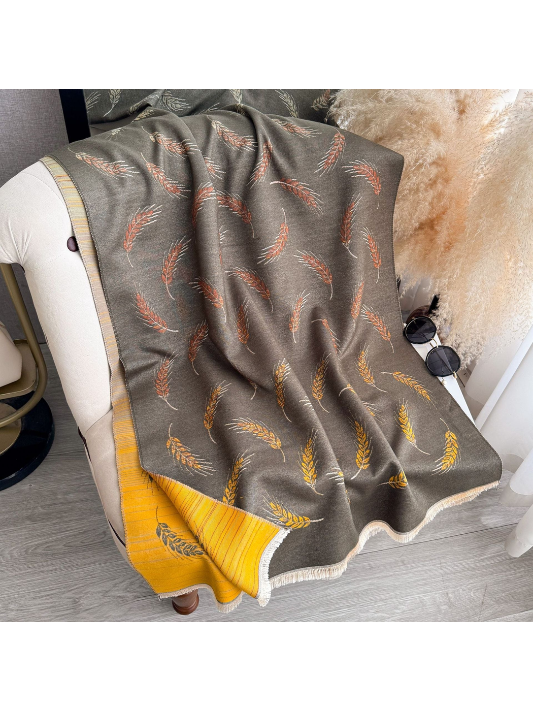Dark Gray scarf spread over a chair with wheat motifs, a mustard striped reverse, and fringed edges