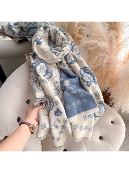 Light Blue floral and paisley scarf held by a hand, with its contrasting reverse side and fringe visible