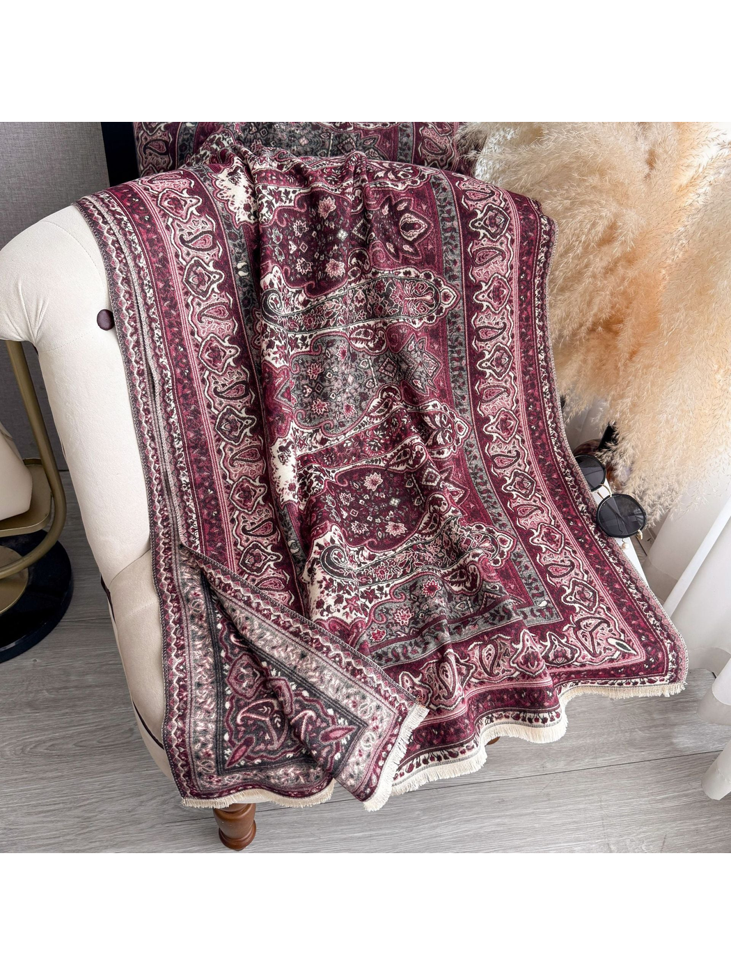 Burgundy paisley scarf with fringed edges draped over a chair