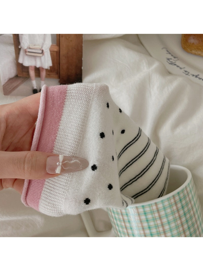 Close-up of a white sock with polka dots and horizontal stripes