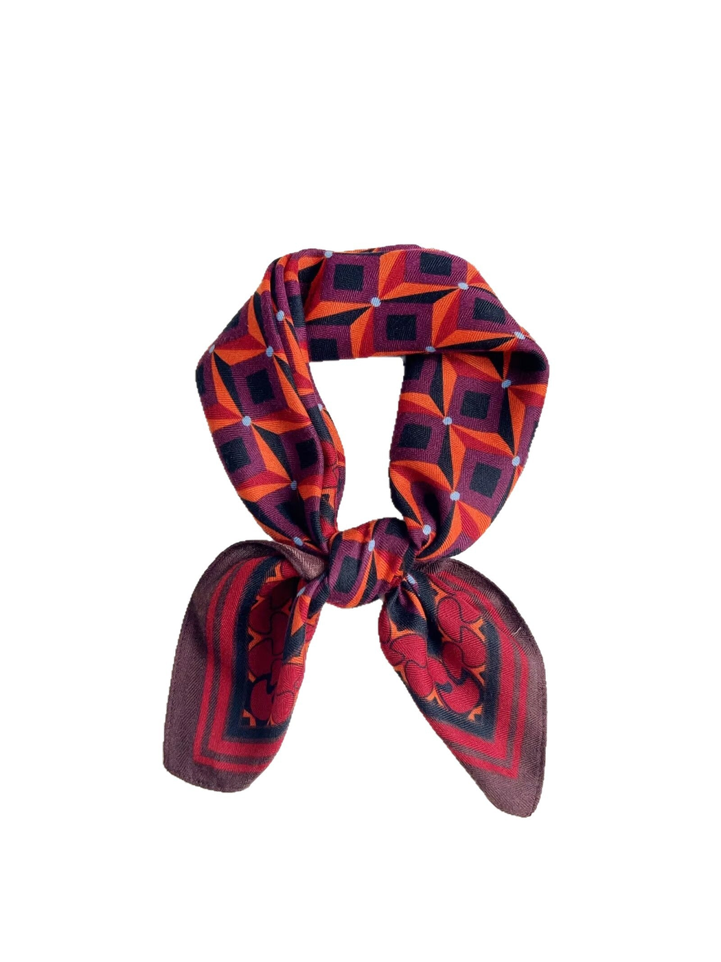 Red, orange, and navy geometric square scarf tied in a bow