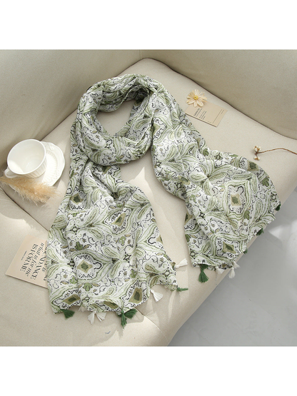 Green paisley scarf with tassel fringe arranged on a sofa