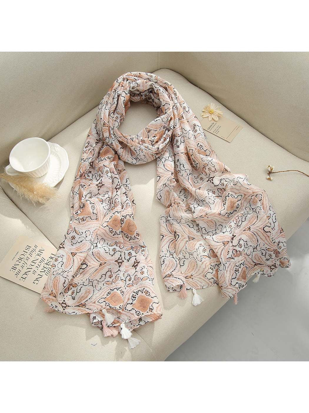 Blush Pink paisley scarf with tassel fringe arranged on a sofa