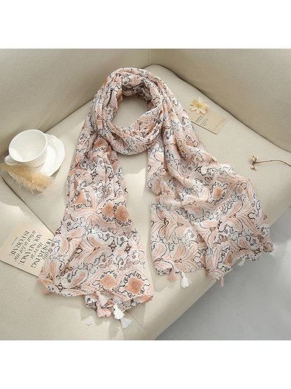 Blush Pink paisley scarf with tassel fringe arranged on a sofa