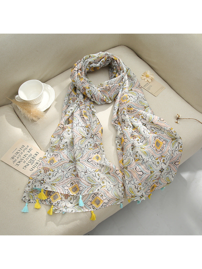 Ivory paisley scarf with tassel fringe arranged on a sofa