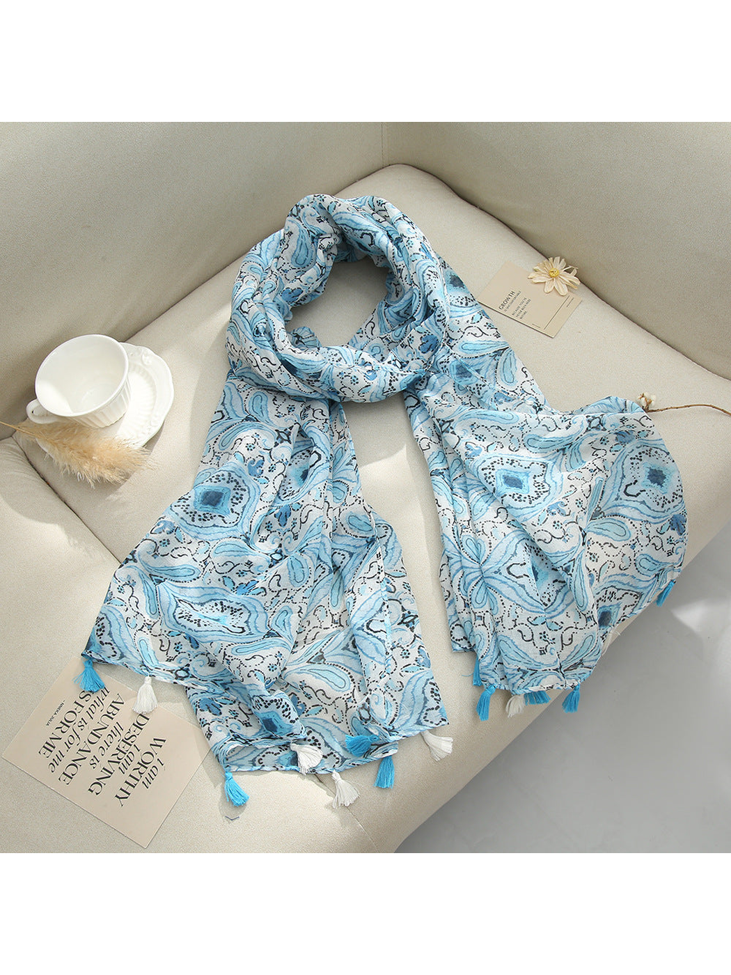 Light Blue paisley scarf with tassel fringe arranged on a sofa