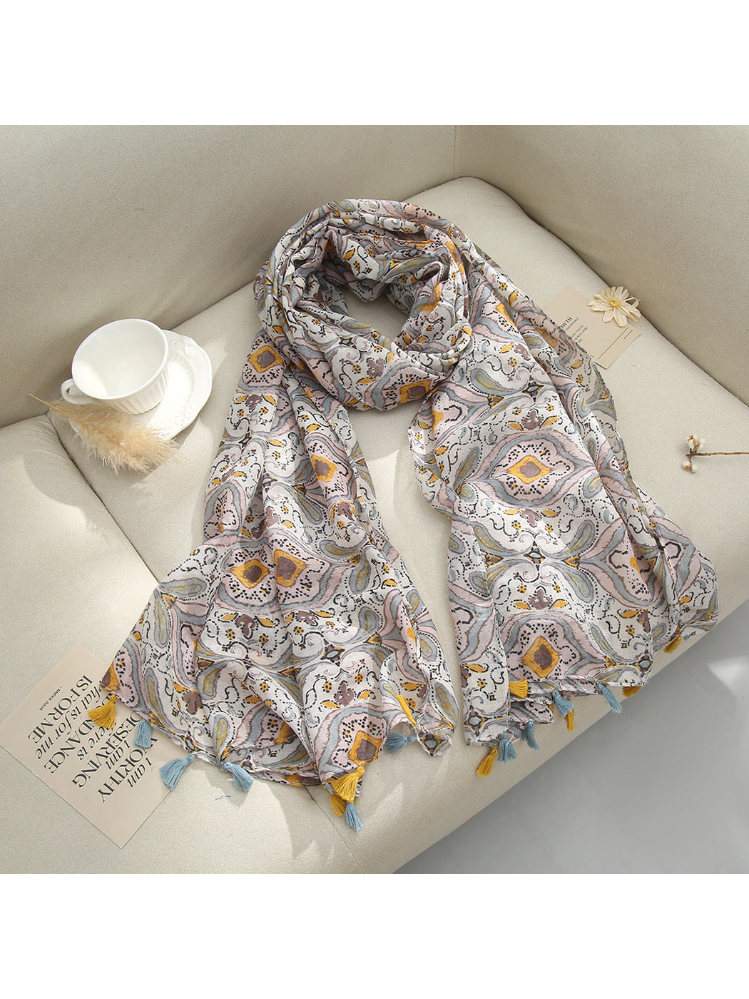 Brown paisley scarf with tassel fringe arranged on a sofa