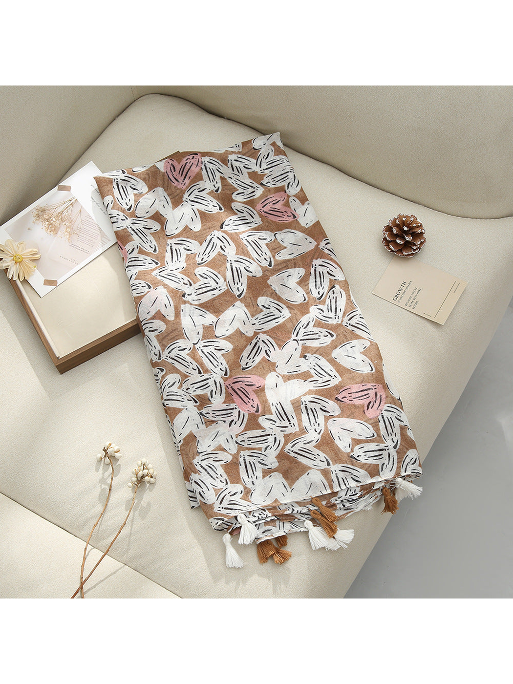 Brown scarf displayed flat with abstract butterfly-like motifs and tassel fringe