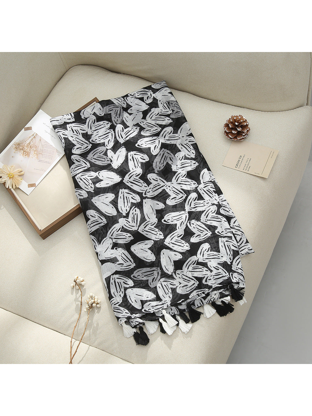 Black scarf displayed flat with abstract butterfly-like motifs and tassel fringe
