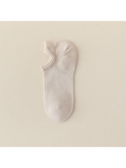 Beige and black Rufia liner socks side by side on white surface