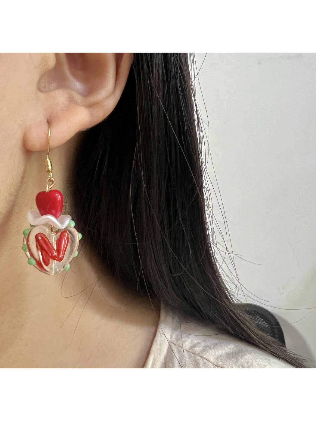 Close-up of Earwish Playful Apple Heart Earrings with red enamel and gold-tone metal