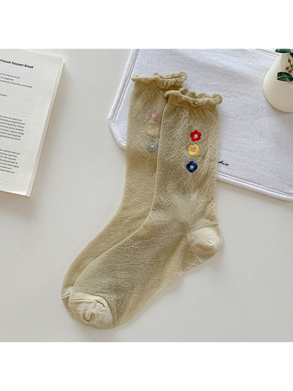 Pair of Rufia Sweet Flower Detail Crew Socks displayed on wooden surface with soft light