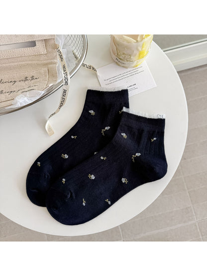 Pair of Rufia soft floral lace trim ankle socks on a wooden surface