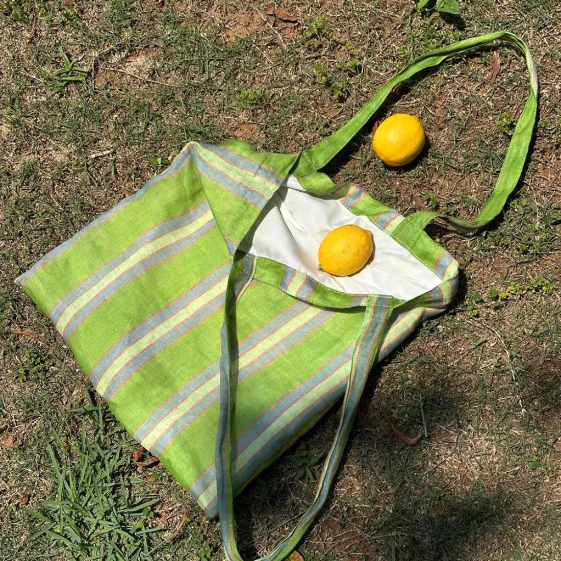 Cosbai striped shoulder tote bag hanging on a hook against white background