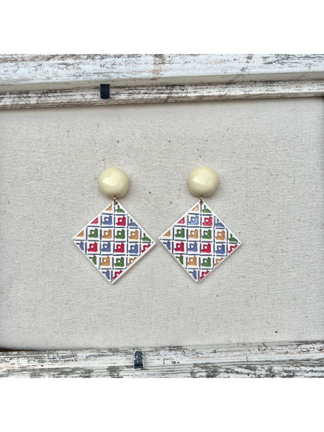 Earwish geometric diamond drop earrings laid flat with soft lighting