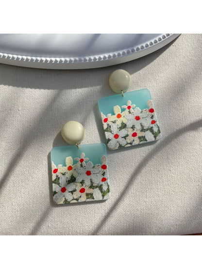 Close-up of Earwish Daisy Field drop earrings with white daisy petals and yellow centers