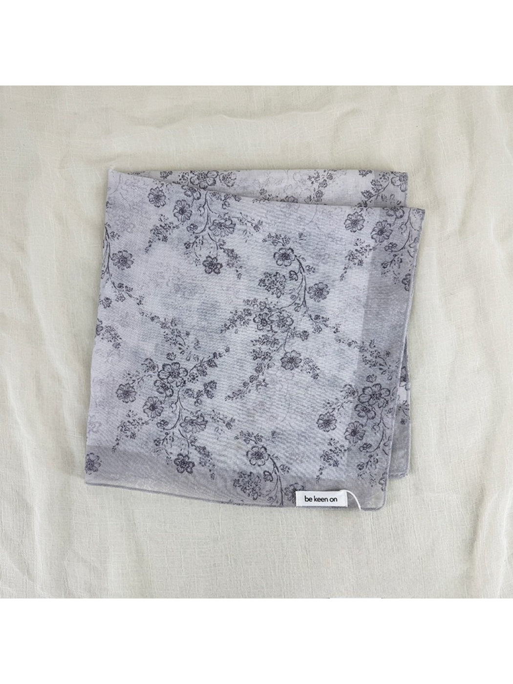 Edge detail of scarf showing fine stitching and soft fabric with blossom print