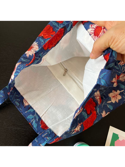 Blue floral shoulder tote bag held by model wearing casual outfit