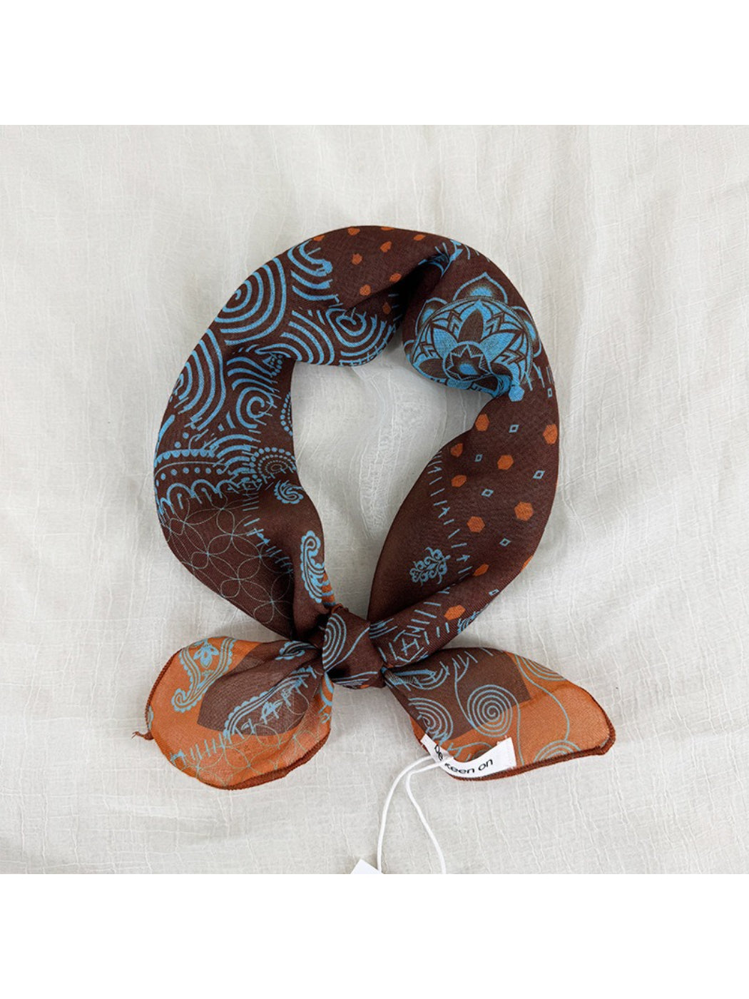 Model wearing Scarvii Patchwork Paisley Square Scarf styled around the neck with visible patchwork design