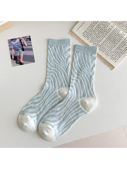 Rufia floral mixed crew socks paired with sneakers on a wooden floor background