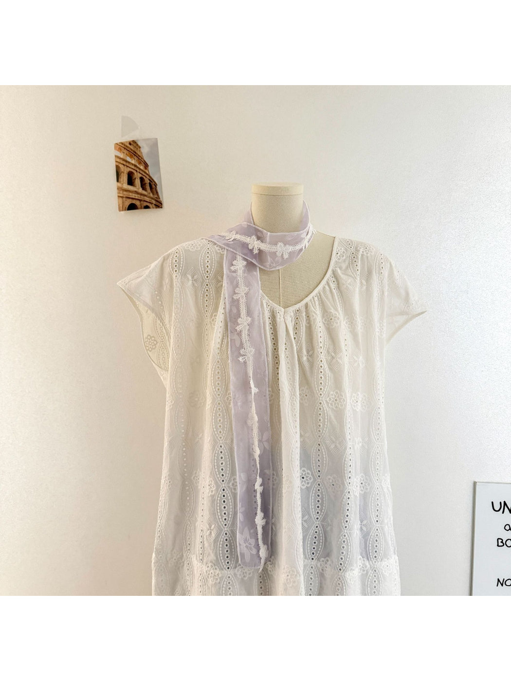 Sheer skinny scarf with floral lace trim draped over a white blouse