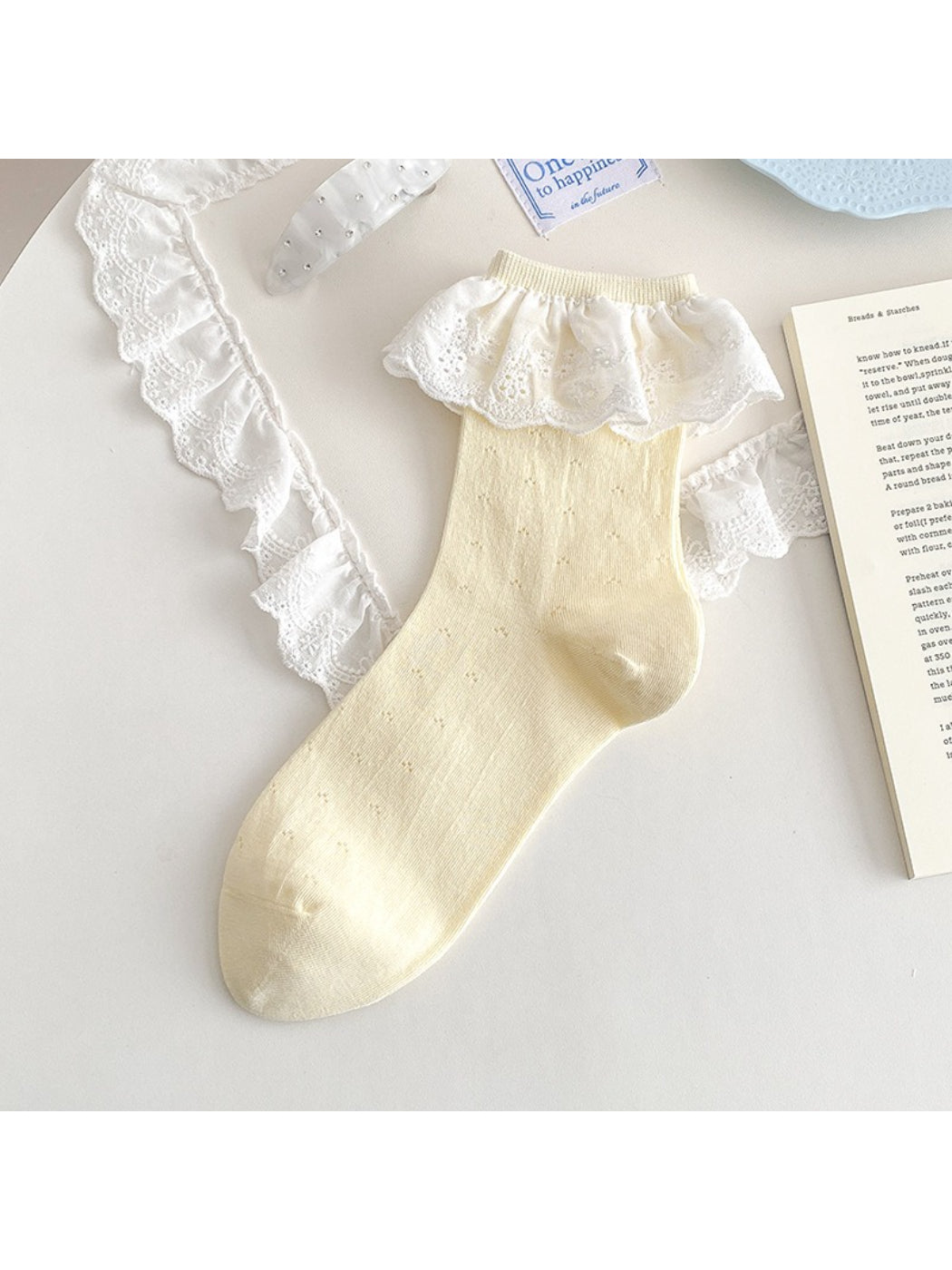 Rufia lace ruffle trim crew socks in white on a light fabric background