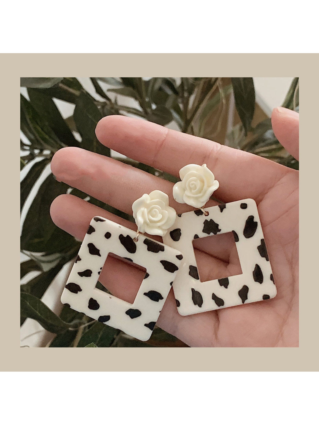 Earwish Cow Print Rose Earrings front view with black and white cow pattern and pink rose detail
