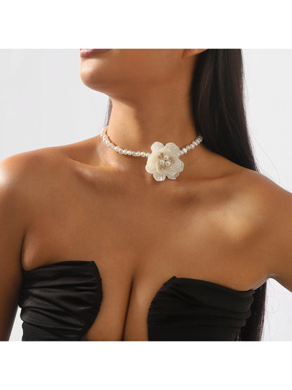 Close-up of white beaded flower necklace with intricate petal design on a white background