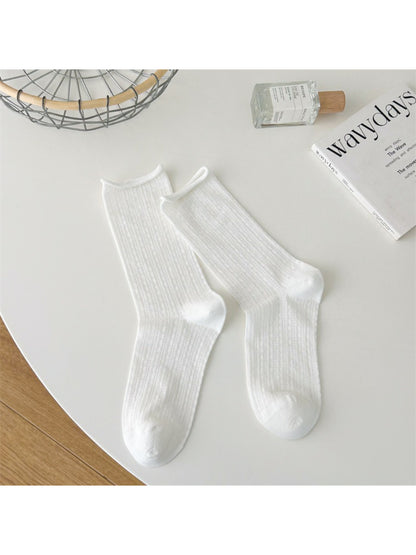 Stack of beige Rufia rolled edge textured crew socks folded neatly