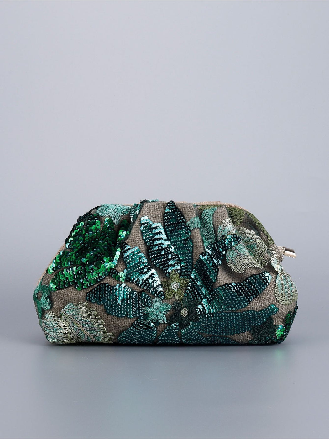 Cosbai clutch bag with floral sequin design resting on elegant fabric background
