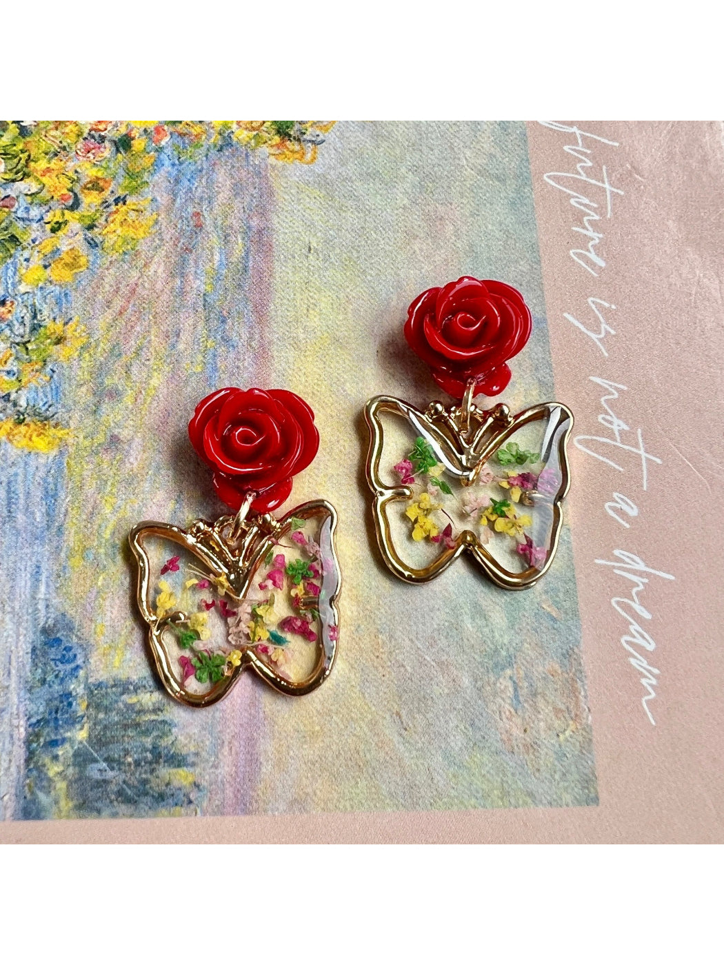 Close-up of Earwish Rose Butterfly Drop Earrings with pink rose and butterfly design