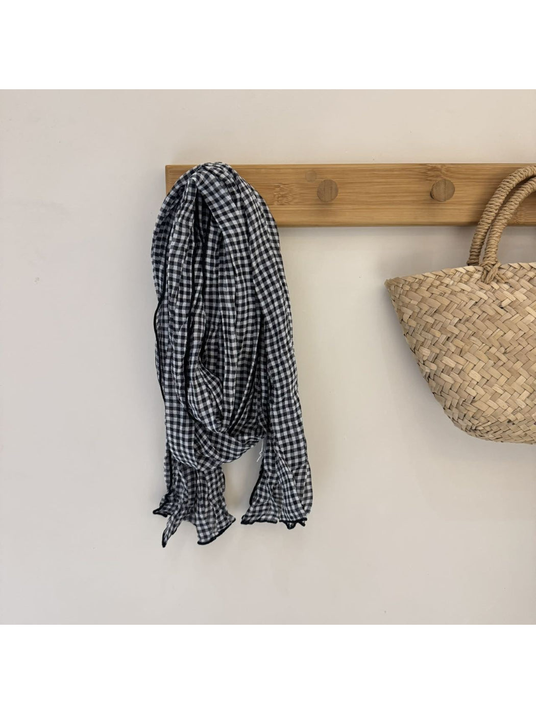 Black and white gingham scarf wrapped around neck with fringed edges visible