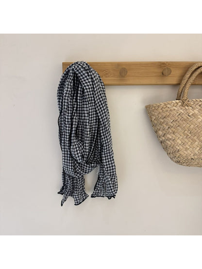 Black and white gingham scarf wrapped around neck with fringed edges visible