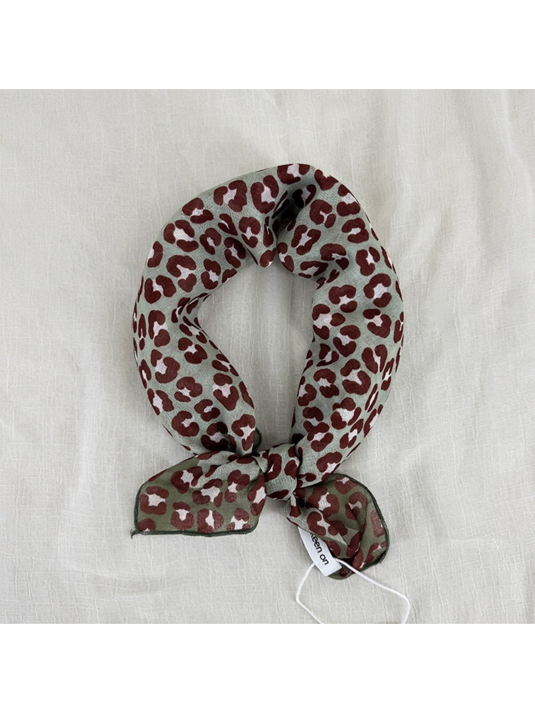 Model wearing Scarvii leopard print square scarf styled around the neck