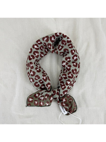 Model wearing Scarvii leopard print square scarf styled around the neck