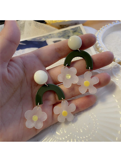 Close-up of green arch daisy earrings with detailed petals and gold hooks