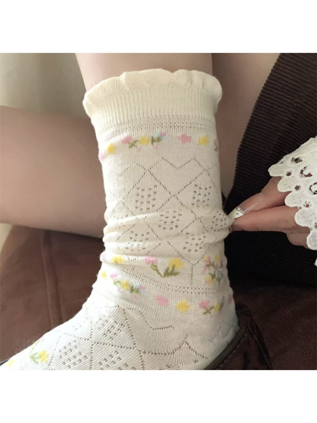 Close-up of Rufia floral pointelle crew socks in cream with pink and green flower pattern