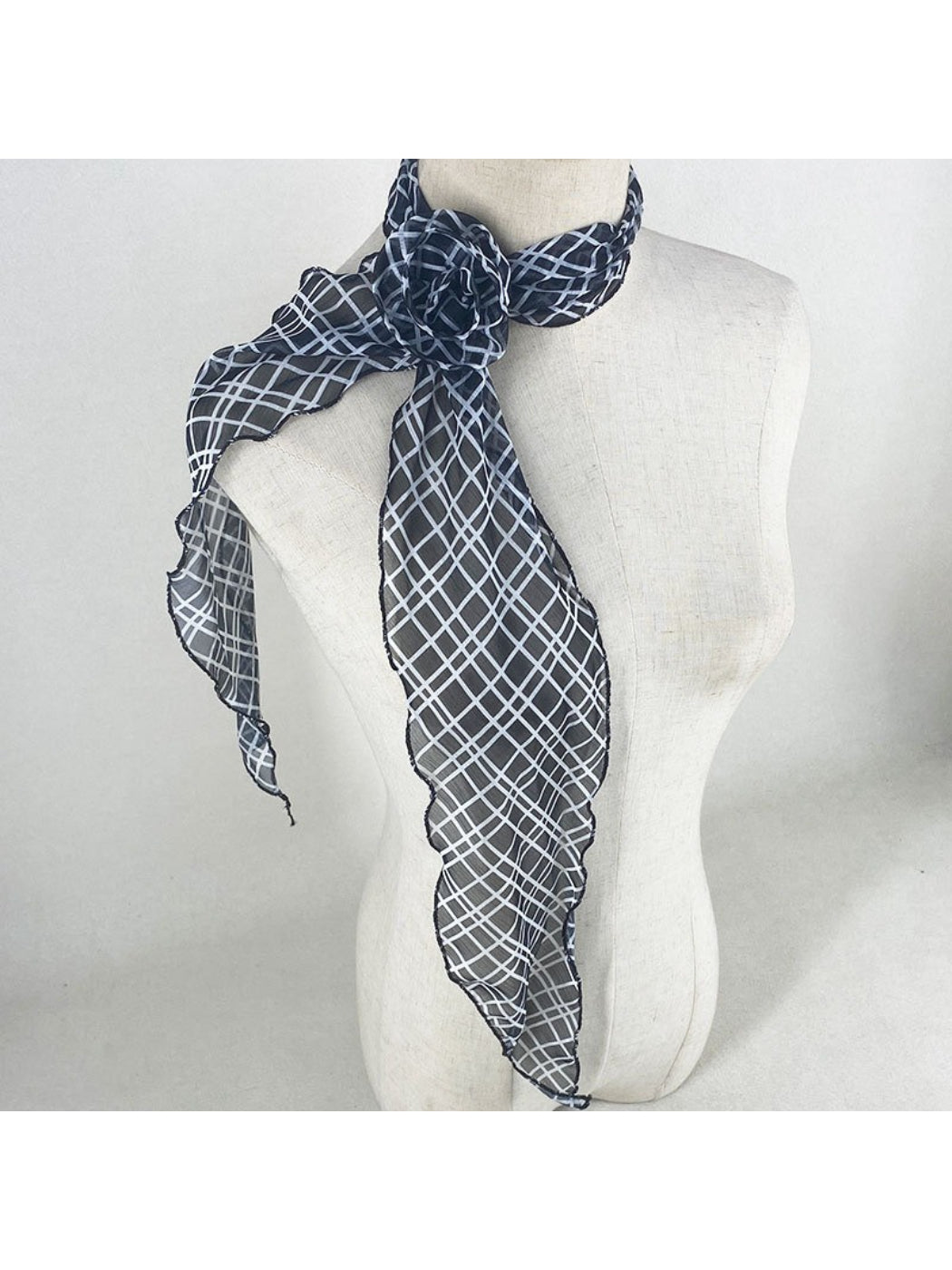 Model adjusting scarf tied around neck with visible rose pattern