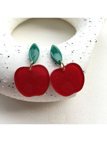 Close-up of red apple-shaped drop earrings with silver hooks on white background
