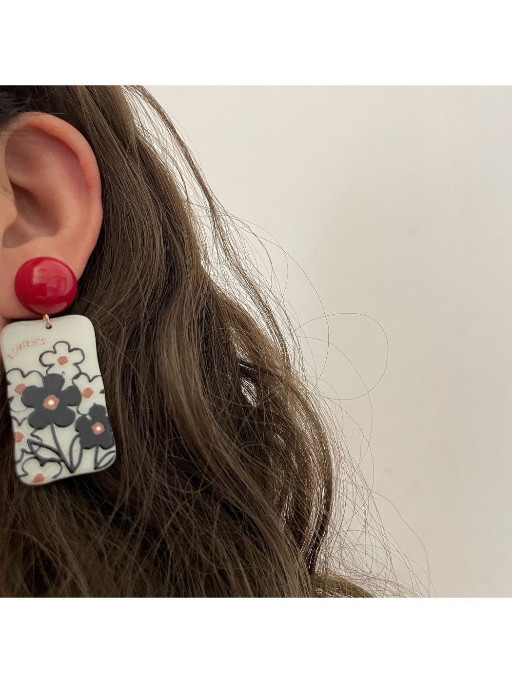 Close-up of Earwish floral drop earrings showing detailed pink flower and green leaves