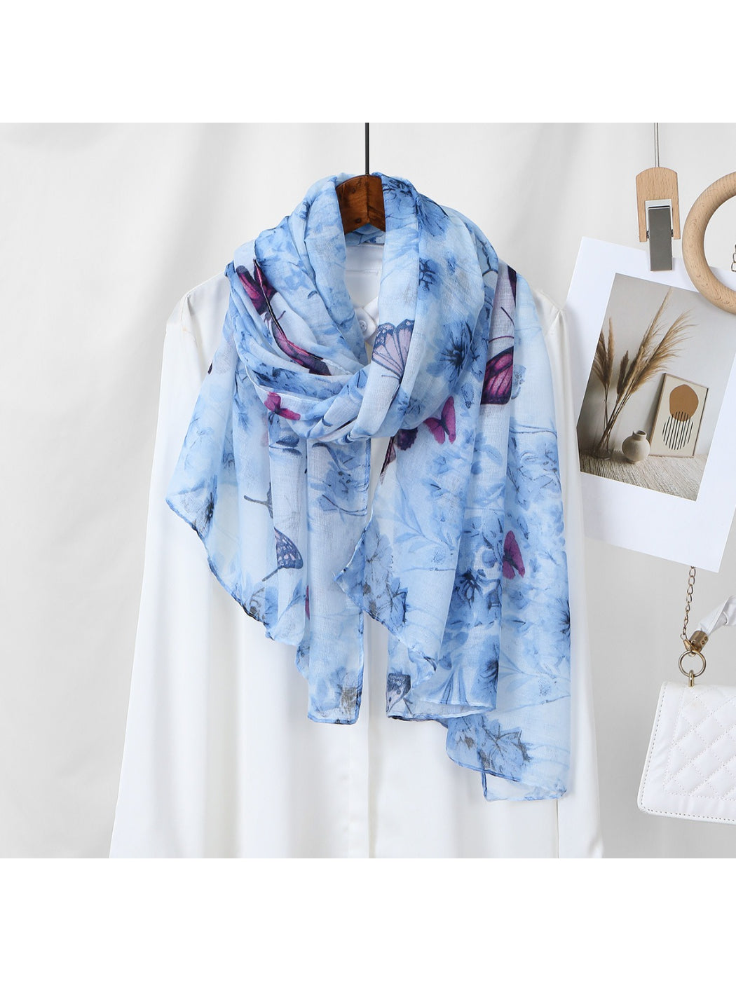 Flat lay of Scarvii lightweight scarf with detailed butterfly and flower illustrations