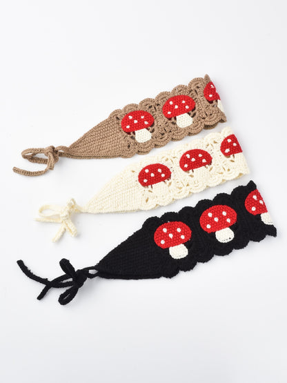 Close-up of Haila crochet mushroom hairband with red and white mushroom design on beige yarn
