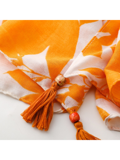 Close-up of two orange tassels and decorative beads on the Floral scarf