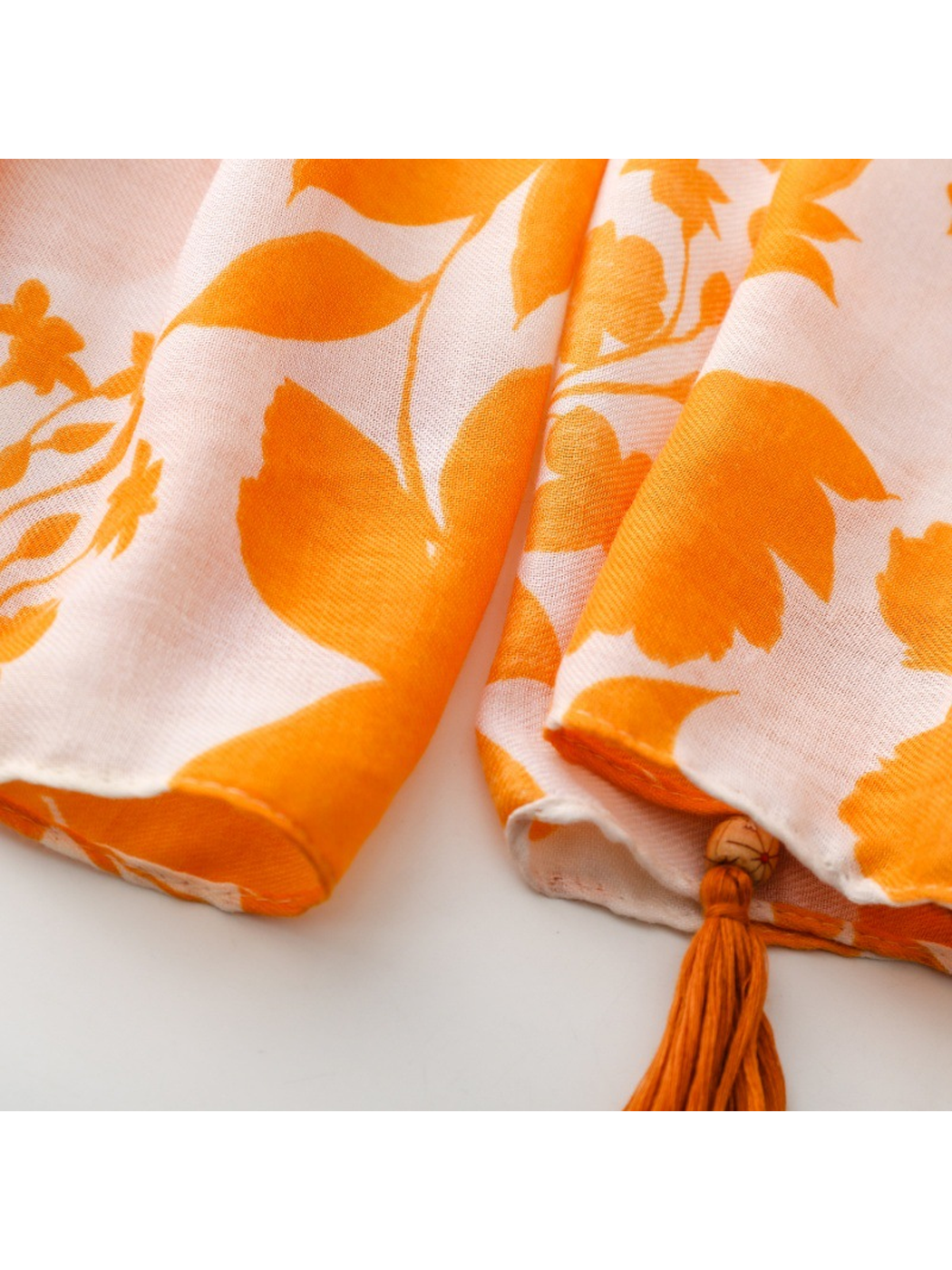 Close-up of the Floral scarf's stitched orange hem and beaded corner tassel