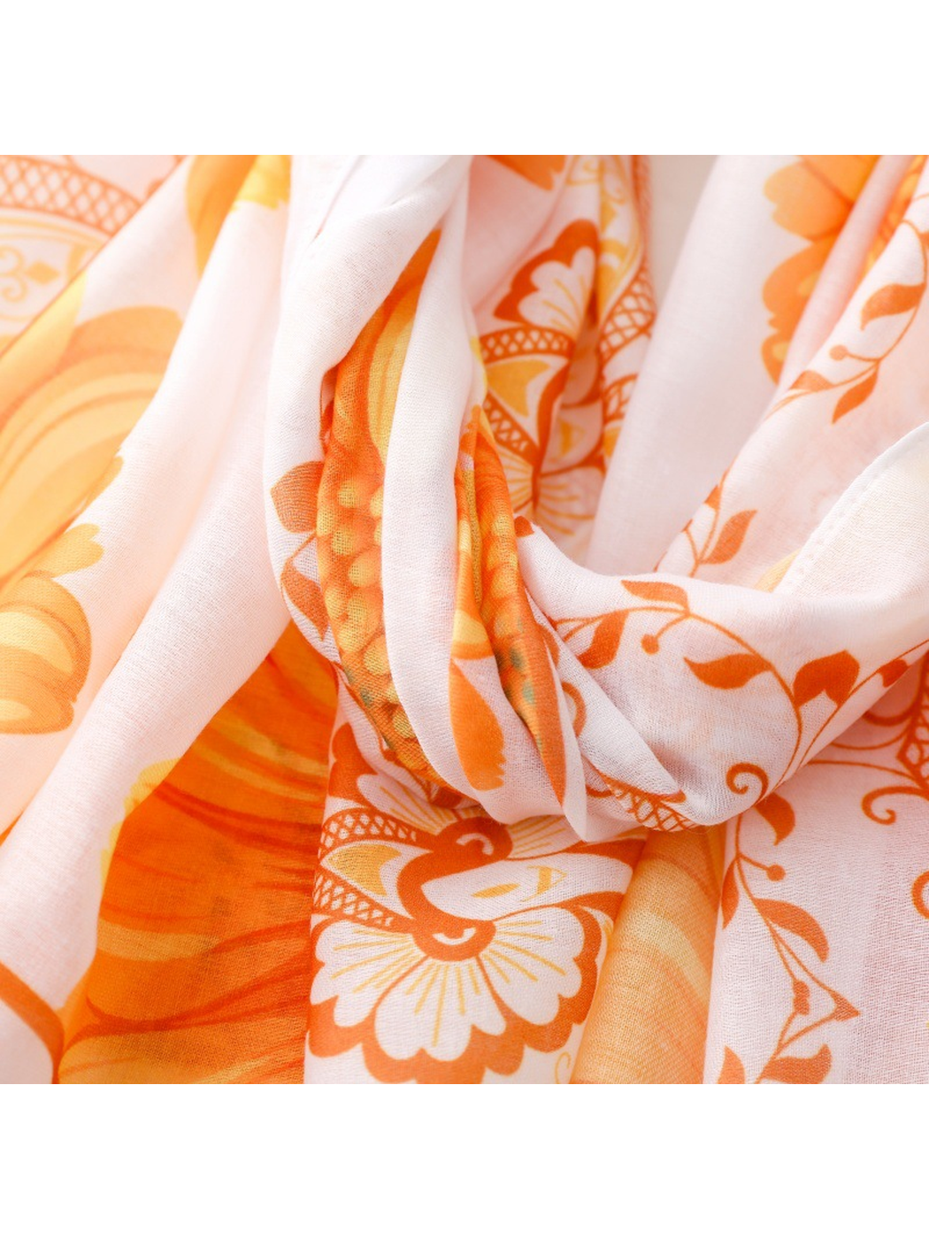 Close-up of the Medallion scarf's orange motifs across white folds