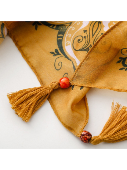 Close-up of two mustard tassels and decorative beads on the Paisley scarf