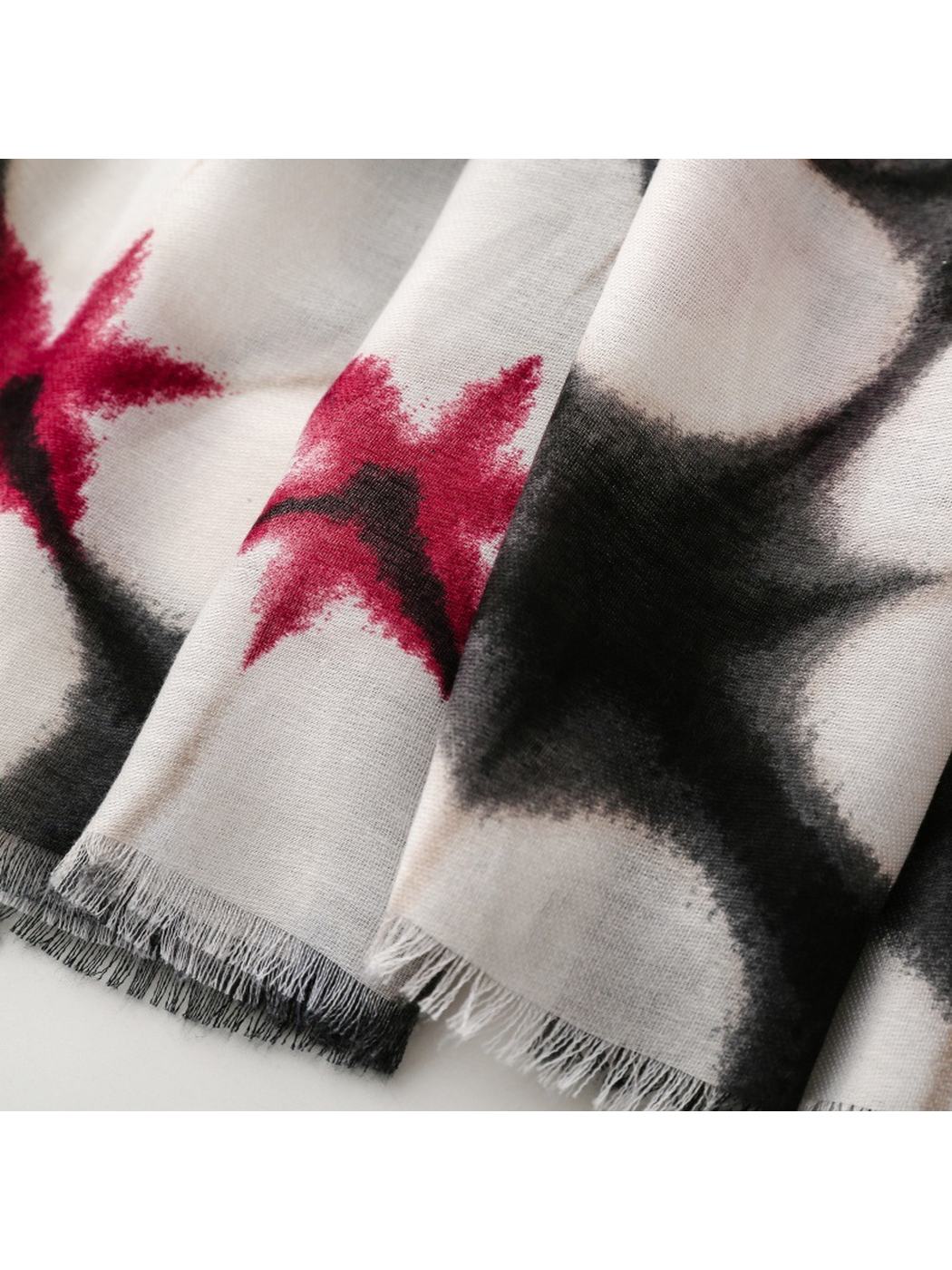 Close-up of the abstract floral scarf's short black and white fringe