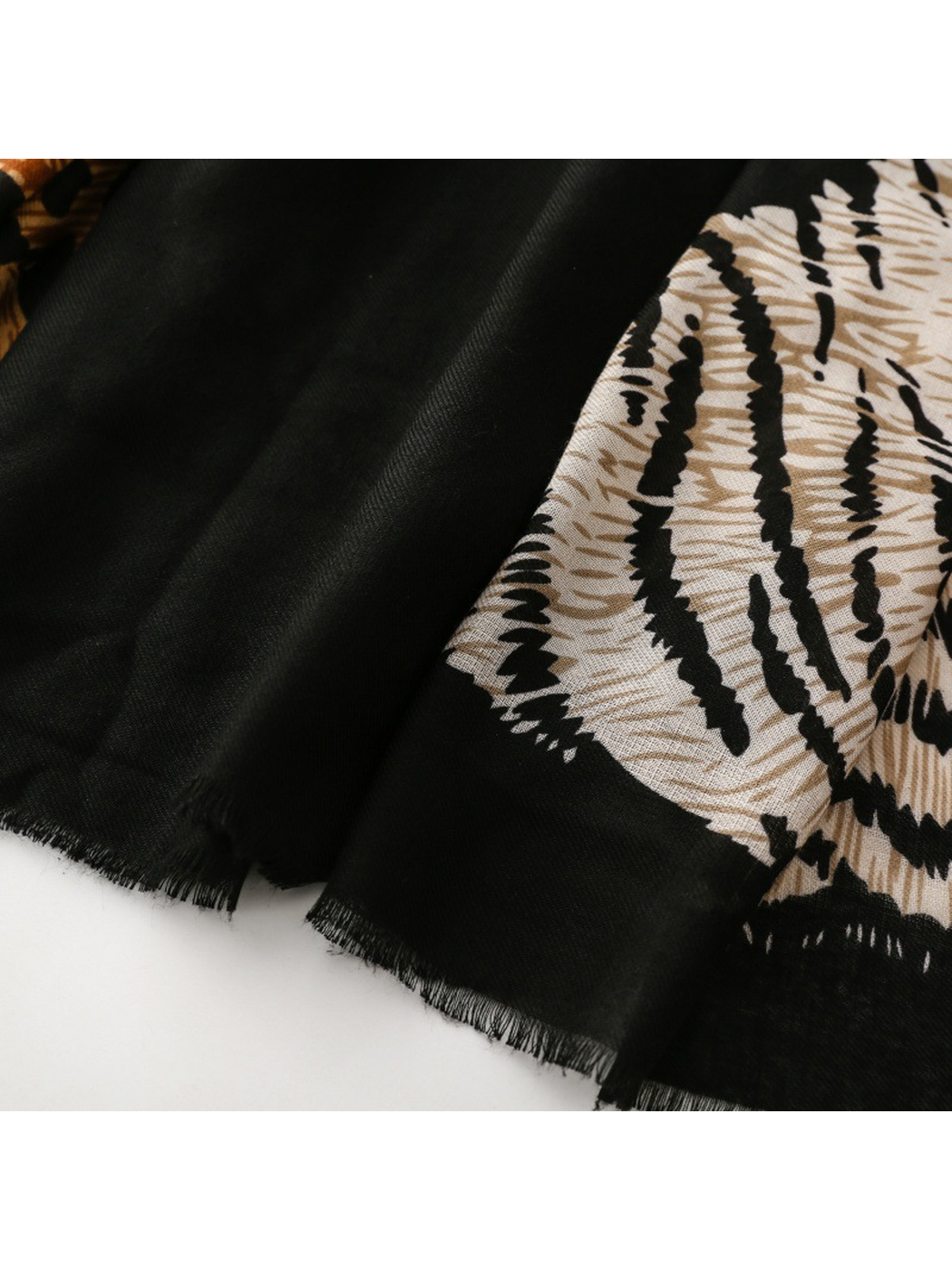 Close-up of Tiger scarf short black fringe beside the cream motif
