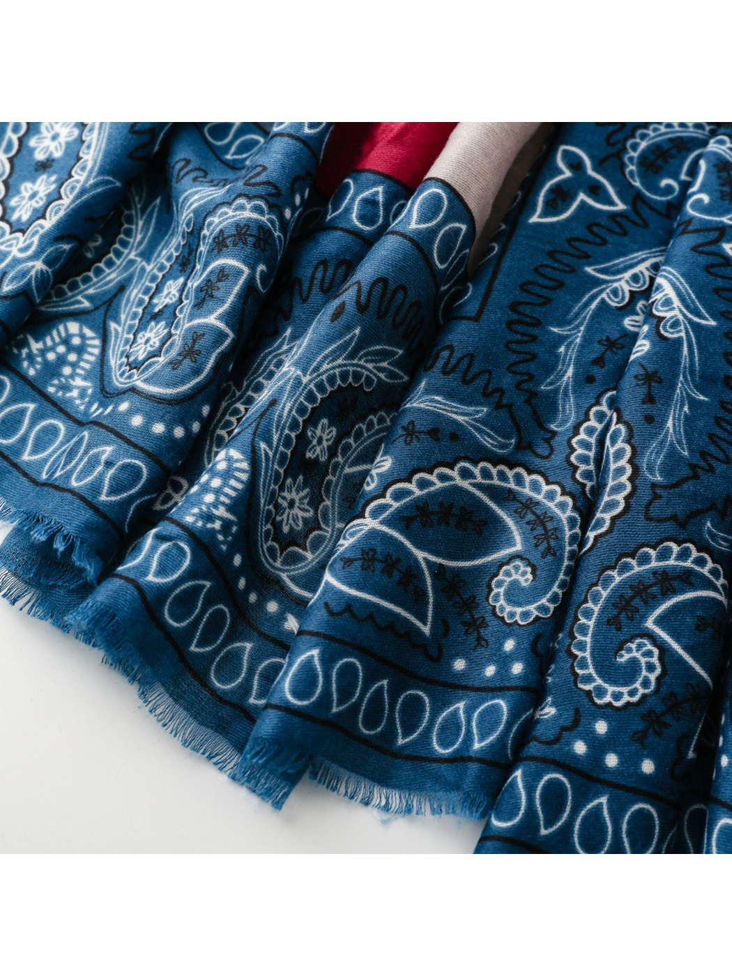Close-up of blue fringe extending from the paisley-printed edge