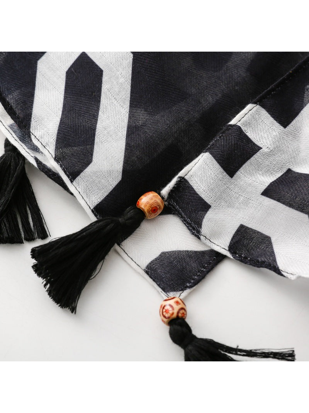 Close-up of black tassels, orange-toned beads and stitched geometric-print hems
